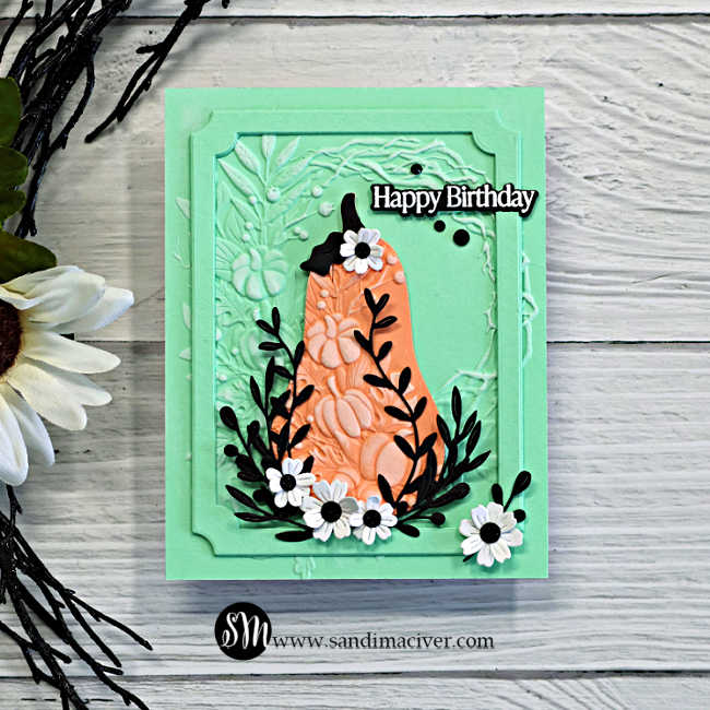 Harvest Heirloom mixed media birthday card in mint and coral, featuring embossed texture, a dimensional notched frame, black leafy branches, and small white flowers.
