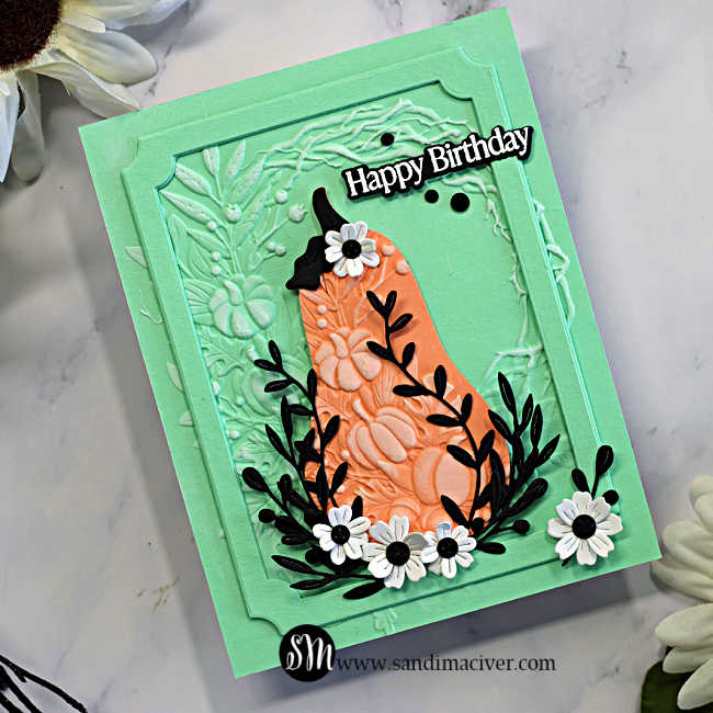 Close-up of a mint and coral Harvest Heirloom mixed media card with embossed details, black leafy stems, white flowers, a notched frame, and Happy Birthday sentiment.