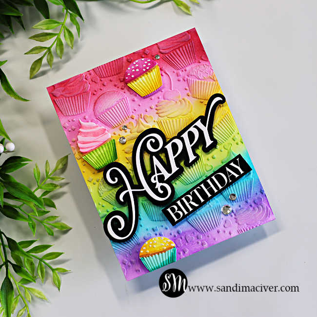 Rainbow ink-blended cupcake birthday card featuring an embossed cupcake background, dimensional cupcakes, and a large black-and-white Happy Birthday sentiment.
