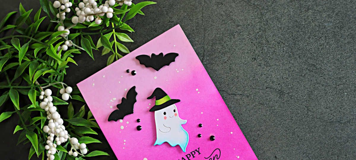 Pink Halloween card featuring a cute white ghost in a witch hat, black die-cut bats, and a bright pink ink-blended background with white splatters.