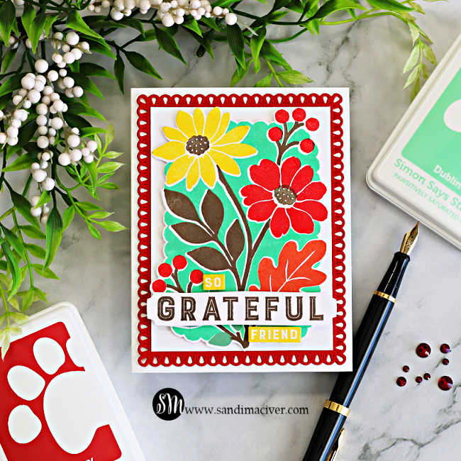 STAMPtember Concord & 9th Incredibly Grateful floral card featuring red and yellow flowers, a mint green background, and a decorative red die-cut frame, styled with ink pads, greenery, and a fountain pen.