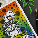 Halloween card featuring a witch-hat cat on a colorful Distress Spray background with black polka dots, bats, and a Happy Halloween sentiment.