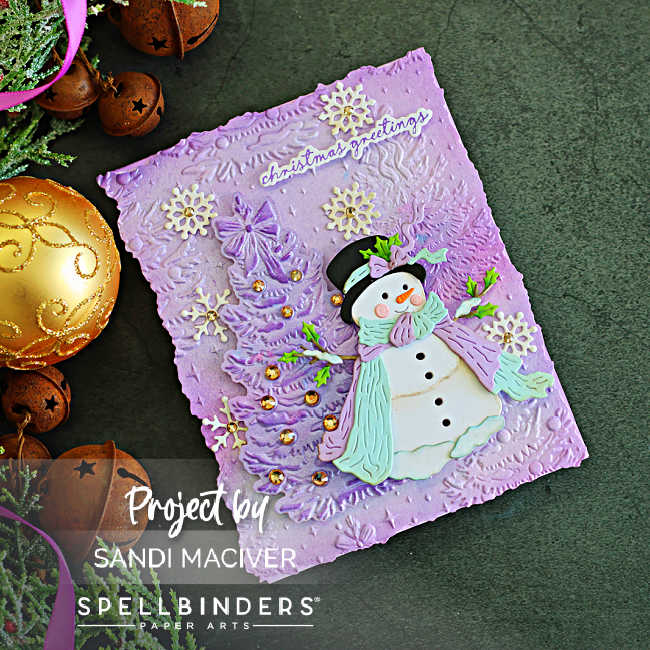 Angled view of a vintage Christmas card with a Sweet Snowman, dimensional lavender tree, distressed embossed background, gold accents and scattered snowflakes.