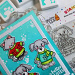 Simon Says Stamp and Newton’s Nook Sweater Season card featuring Copic-colored winter critters in colorful sweaters on a bright aqua snowflake background.