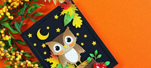 Spellbinders Owl Be There fall card featuring a die-cut owl, colorful autumn leaves, mushrooms, crescent moon and stars on a black background.