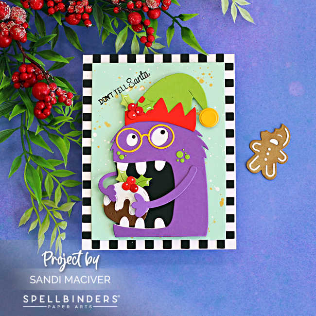 Handmade Merry Munchies Christmas card featuring purple Chompster in a red and green elf hat holding Christmas pudding, with a splattered mint background, black-and-white checkerboard border, and “Don’t Tell Santa” sentiment.