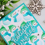 Cozy snowman Christmas card featuring embossed and stenciled snowmen in teal and green, a Holiday Wishes sentiment, sparkling gems, greenery, and snowflake accents.