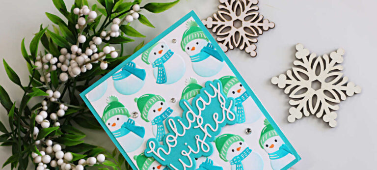 Cozy snowman Christmas card featuring embossed and stenciled snowmen in teal and green, a Holiday Wishes sentiment, sparkling gems, greenery, and snowflake accents.