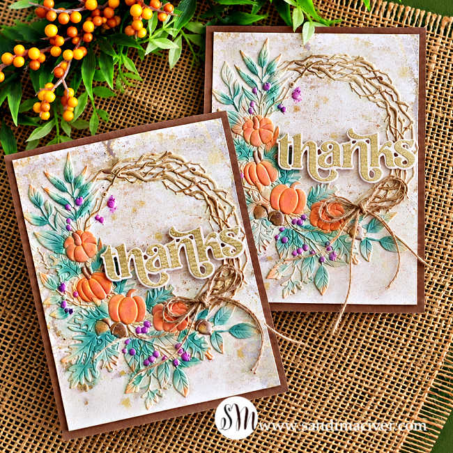 Two handmade fall thank-you cards featuring embossed pumpkin wreaths, soft teal foliage, purple berries, twine bows, and gold “thanks” sentiments on a rustic burlap background.