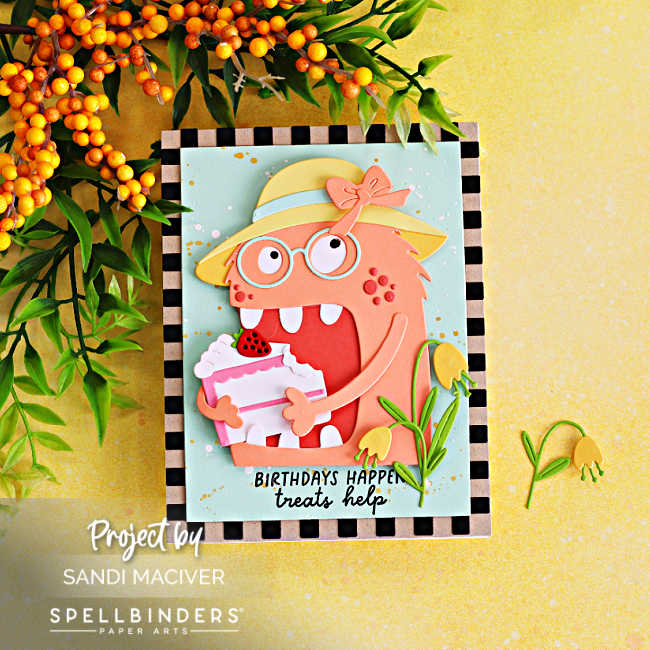Handmade birthday card featuring coral Mrs. Chompster in a yellow sunhat holding strawberry cake, with yellow flowers, a splattered mint background, kraft-and-black checkerboard border, and “Birthdays happen, treats help” sentiment.