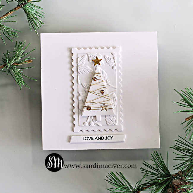 White-on-white Simple Trees Christmas card with a gold-thread-wrapped tree, gold gems and stars, an embossed leaf-and-berry panel, a postage-edge frame, and a “Love and Joy” sentiment.