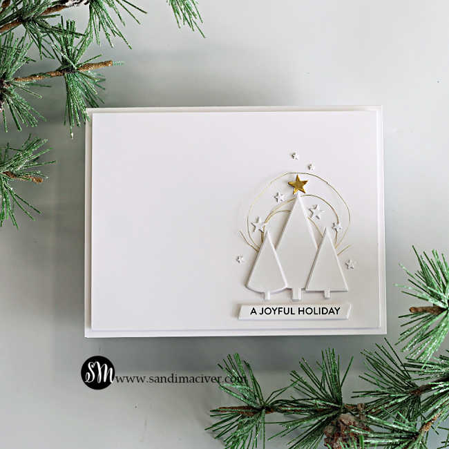 White-on-white Simple Trees Christmas card featuring three dimensional die-cut trees, loops of gold thread, scattered white stars, a gold star topper, and an “A Joyful Holiday” sentiment.