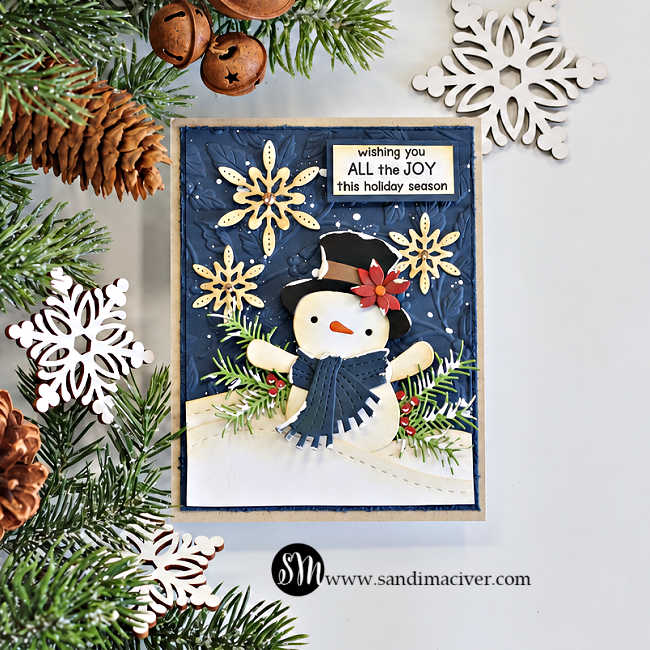 Vintage masculine Christmas card featuring a die-cut snowman in a black top hat and navy scarf, cream snowflakes, evergreen sprigs, and red berries against an embossed navy background, with the sentiment “Wishing you all the joy this holiday season.”