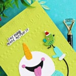 Funny snowman Christmas card featuring a colorful die-cut snowman and bird on a bright green embossed background with “The Nog Made Me Do It” sentiment.