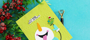 Funny snowman Christmas card featuring a colorful die-cut snowman and bird on a bright green embossed background with “The Nog Made Me Do It” sentiment.