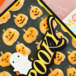 Halloween card featuring orange jack-o’-lanterns on a black embossed background, layered Spooky sentiment, and white ghost die-cut.
